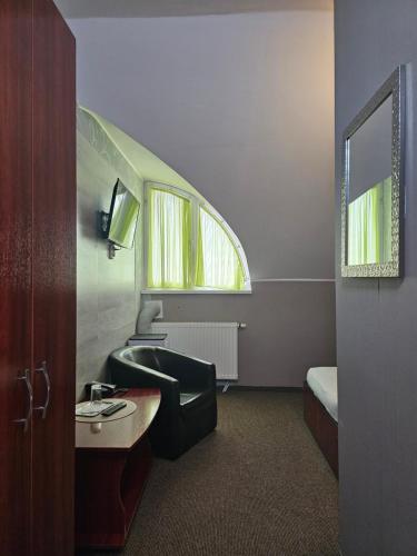a room with a chair and a desk and a window at Pension Regal in Satu Mare