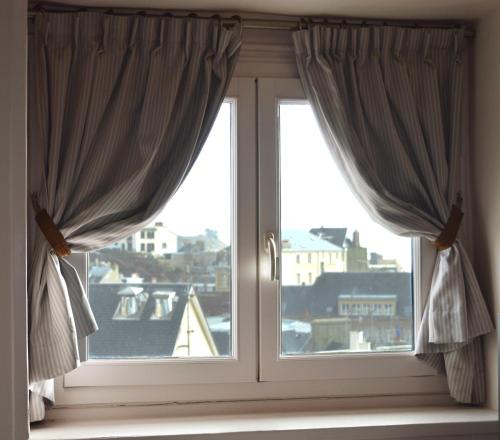 a window with curtains and a view of a city at Hotel Des Bains in Granville