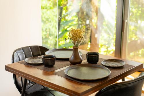 a wooden table with plates and a vase with flowers on it at Villa SACHIIBARU 浜辺の茶屋 の 宿 in Nanjo