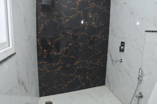 a bathroom with a shower with a black marble wall at The Ora Hotel in Vrindāvan