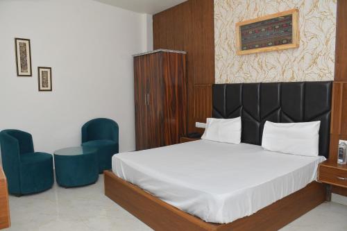 a bedroom with a bed and two blue chairs at The Ora Hotel in Vrindāvan