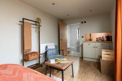 a bedroom with a bed and a table and a kitchen at Cotswolds Cabin in Stonesfield
