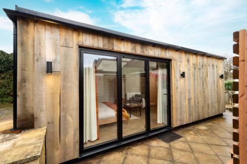 a wooden house with glass doors on a patio at Cotswolds Cabin in Stonesfield