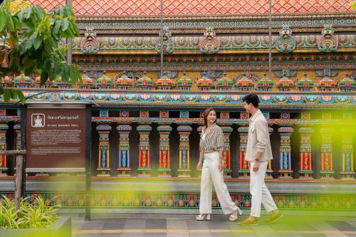 a man and a woman walking in front of a building at Holiday Inn Bangkok Silom by IHG in Bangkok