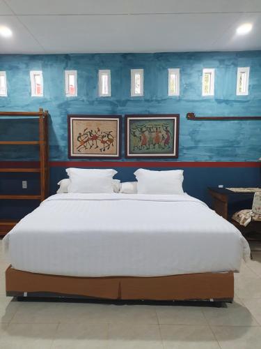 a bedroom with a large white bed with blue walls at Ruma Kaca Simanindo Bed&Breakfast in Panjaitan