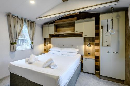 a bedroom with a large bed with white sheets at Landal Kenwick Woods in Louth