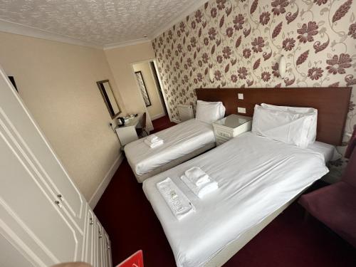 two beds in a hotel room with white sheets at Silversands Hotel in Blackpool