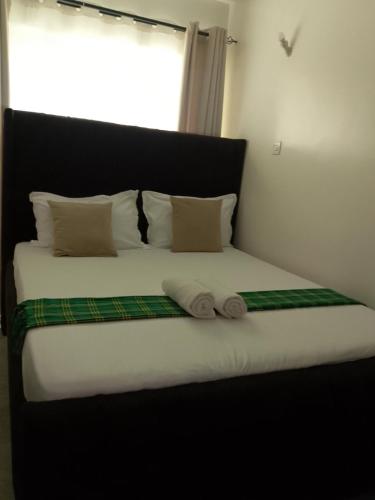 a bed with two towels on it with a window at Serenity Brown Pad in Kiambu