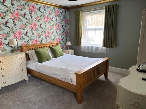 a bedroom with a bed with a floral wallpaper at Keats Green Hotel in Shanklin