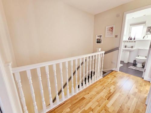 a white staircase in a home with wooden floors at Modern 5 Bedroom Townhouse with Free Parking in Glasgow