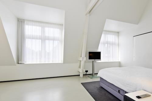 a white bedroom with a bed and a mirror at Urban Residences Maastricht in Maastricht