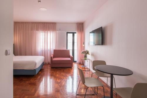 a hotel room with a bed and a table and chairs at LSA Campos by Numa in Lisbon