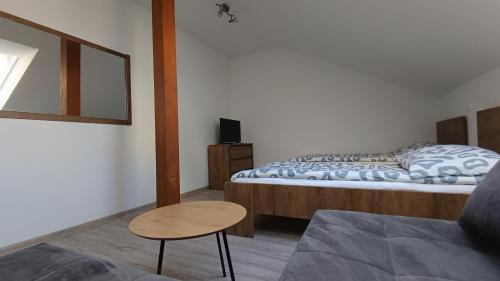 a room with two beds and a table and a chair at Apartmány U Stadionu in Šumperk