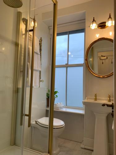 a bathroom with a toilet and a window and a sink at Chy Sabona - Front Room in Penzance
