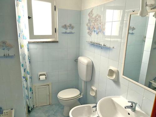 a white bathroom with a toilet and a sink at Valledoria holiday flats in Valledoria
