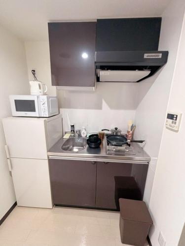a small kitchen with a sink and a microwave at 551 Namba in Osaka