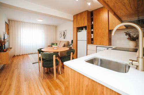 a kitchen with a sink and a table with chairs at Magníficos Dias Atlânticos Studio in Moledo