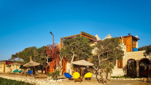 a building with chairs and umbrellas in front of it at Riad Golden Baibah in Zaouia Akermoud