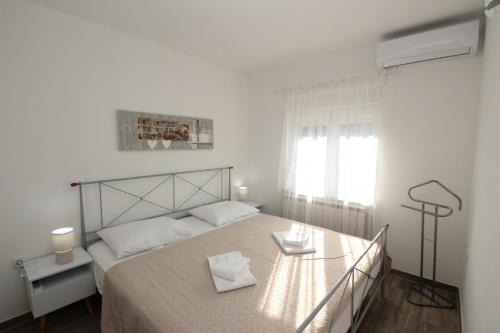 a white bedroom with a bed and a window at Sea side Punat in Punat