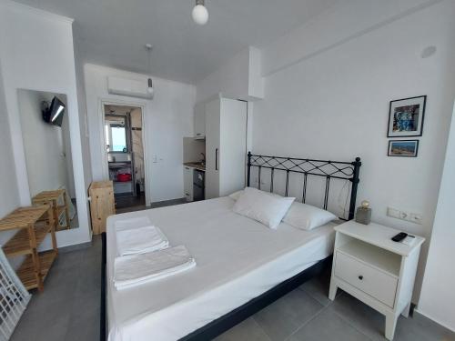 a bedroom with a large white bed and a table at Kedros -Small Seaside Studio -Ground Floor in Elafonisos