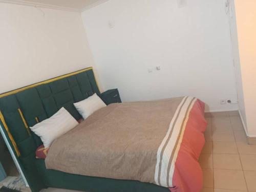 a bedroom with a green bed with pillows at Chambre aménagée dans un hôtel in Douala