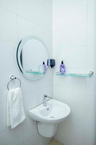 a white bathroom with a sink and a mirror at Timeless Residency in Zanzibar City