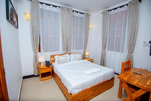 a bedroom with a bed and a desk and windows at Timeless Residency in Zanzibar City