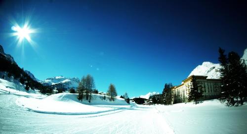 a snow covered slope with a building in the background at Maloja Palace Residence Engadin-St Moritz CO2-Neutral in Maloja