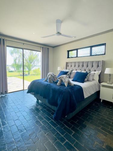 a bedroom with a large bed with blue pillows at Vaal Dam Manor - Waters Edge in Oranjeville
