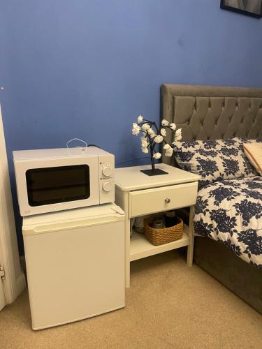 a microwave on top of a table next to a bed at Urban Blue by Wolverhampton Train Station in Wolverhampton