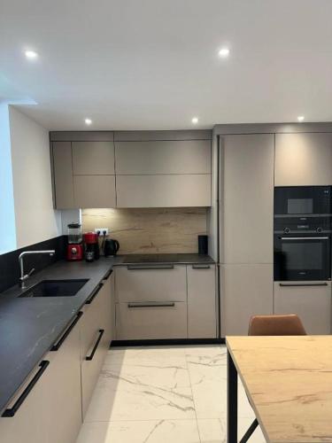 Eiffel Tower Accommodation Design في باريس: مطبخ بخزائن بيضاء وطاولة خشبية