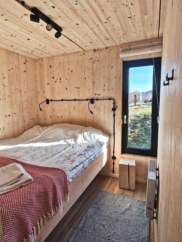 a bed in a wooden room with a window at Domek Fika in Laskowa