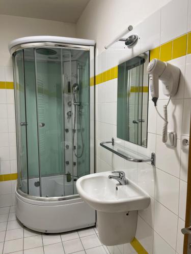 a bathroom with a glass shower and a sink at Penzion Luna in Brno
