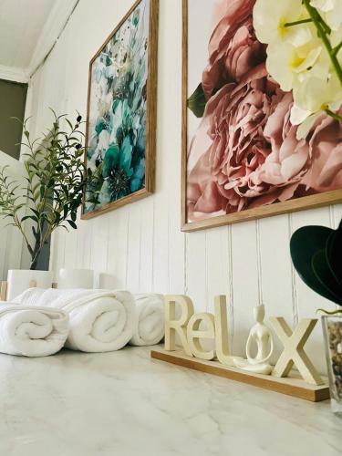 a room with two paintings and a wooden sign that reads relax at Briar & Bloom2 in Hilton