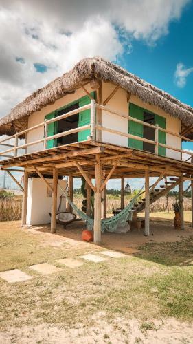 a house with a thatched roof with a hammock in front at Villa Água Viva in Itarema