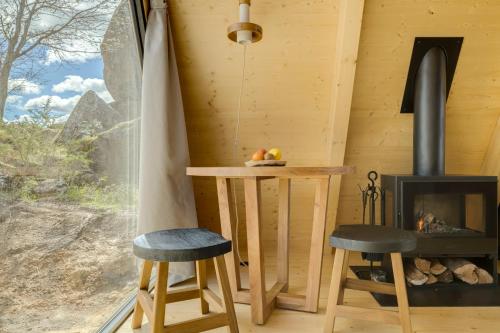 a room with a table and two stools and a fireplace at TheVagar - Glamping Mountain Shelters in Belmonte