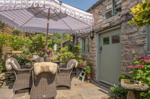 a patio with a table and chairs and an umbrella at Helmsley Garden Cottage & Railway Carriage in Helmsley