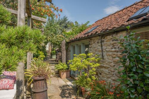 a stone house with plants in front of it at Helmsley Garden Cottage & Railway Carriage in Helmsley