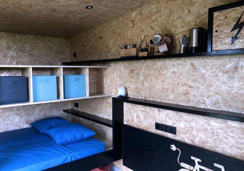 a room with a bed with blue pillows and shelves at Cyclodges – Marguerite et Ferdinand in Hotton