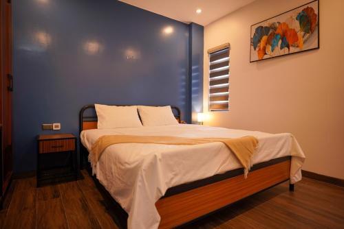 a bedroom with a large bed with a blue wall at Hotel Golden Joy Stay in Hai Phong