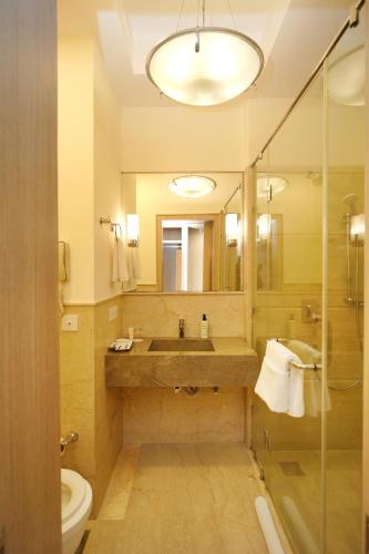 a bathroom with a sink and a toilet and a mirror at Muse Sarovar Portico Nehru Place in New Delhi