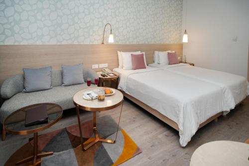 a hotel room with a bed and a couch at Muse Sarovar Portico Nehru Place in New Delhi