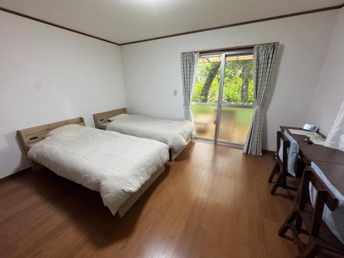 two beds in a small room with a window at Kuganipi Beachside Inn Iriomote in Iriomote