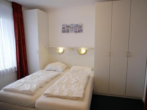 a bedroom with two beds and a cabinet at Badhotel Appartementen Callantsoog in Callantsoog