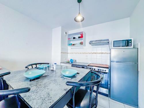 a kitchen with a counter with chairs and a refrigerator at Apartment 4 pers avec Terrasse in Sète