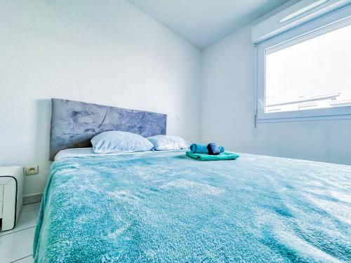 a bedroom with a bed with a blue blanket and a window at Apartment 4 pers avec Terrasse in Sète