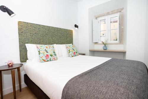 a bedroom with a large white bed and a window at Hermitage Castelo - Casa Saint Jorge in Lisbon
