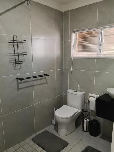 a bathroom with a toilet and a glass shower at 6 Bayview Seaside Apartment in East London