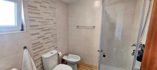 a bathroom with a toilet and a glass shower at Casinha do Cercal in Cercal