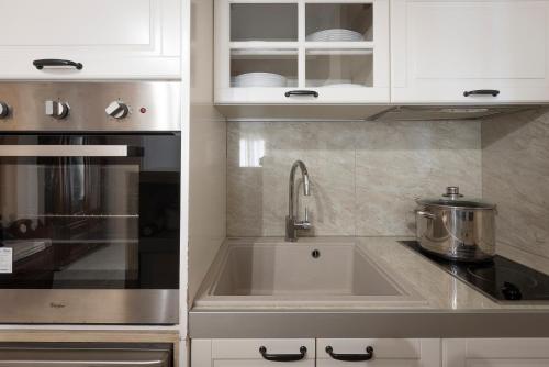 a kitchen with white cabinets and a sink at vintege style apartment in Thessaloniki